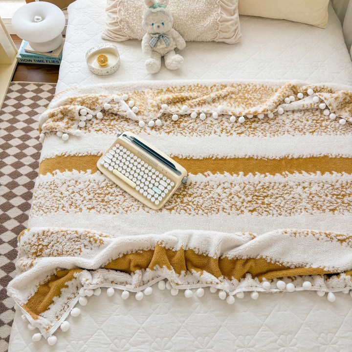 Structured throw blanket with pom-pom details