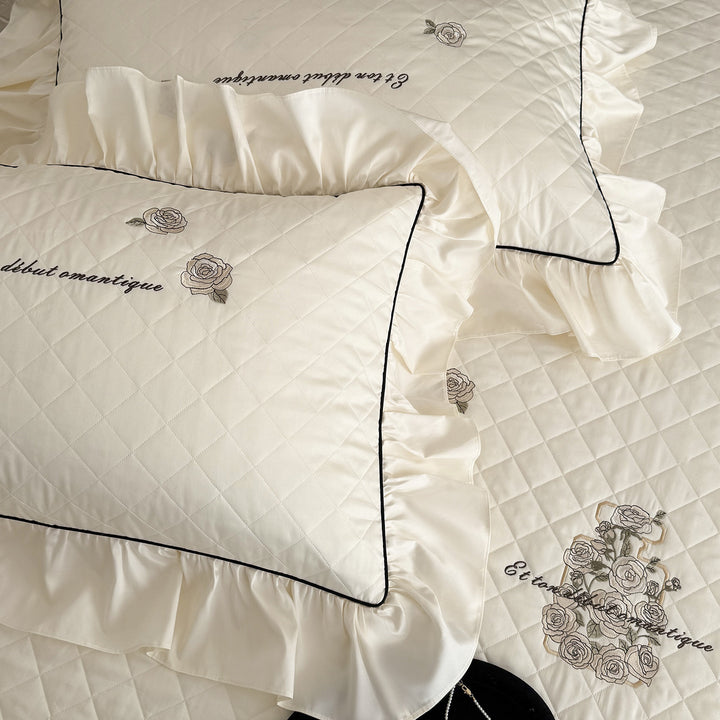 Quilted bedspread set with ruffled hem and embroidered rose motif