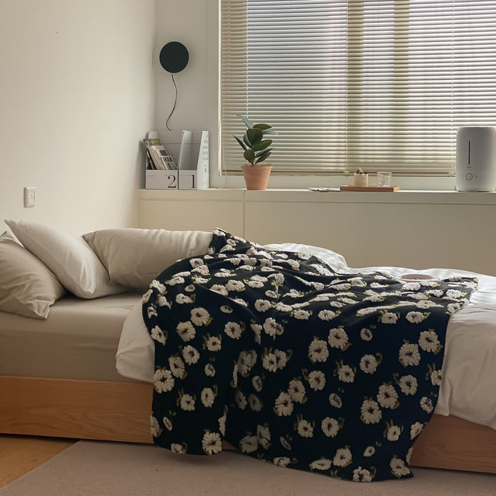 Patterned throw blanket with woven flower appliqués