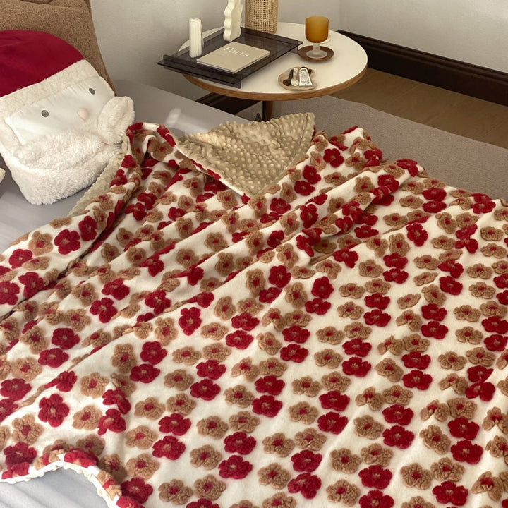 Patterned throw blanket with woven flower appliqués